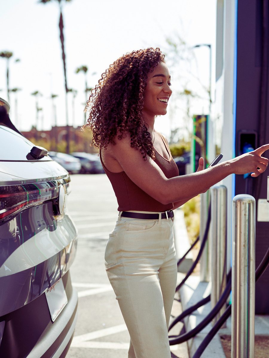 A driver charging an electric vehicle at a public charger